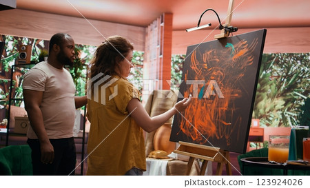 Team of artists in a gallery atelier working on new art piece, using finger painting technique for abstract creation. Blending acrylic paints with precision to create contemporary design. Camera B. Team of artists in a gallery atelier working on new art piece, using finger painting technique for abstract creation. Blending acrylic paints with precision to create contemporary design. Camera B. 123924026
