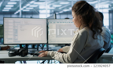 IT professional in server hub ensuring valuable data remains shielded from potential threats using PC. Employee safeguarding data center against unauthorized access and vulnerabilities, camera A IT professional in server hub ensuring valuable data remains shielded from potential threats using PC. Employee safeguarding data center against unauthorized access and vulnerabilities, camera A 123924057