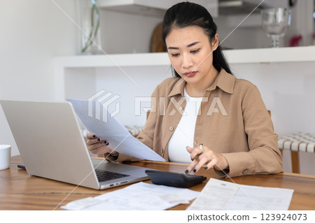 Serious focused Asian freelance bookkeeper woman working from home Serious focused Asian freelance bookkeeper woman working from home 123924073