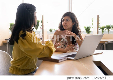 Young female student interact with peer in study using notebook Young female student interact with peer in study using notebook 123924102