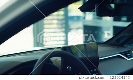 Close up of car interior with steering wheel and infotainment system screen. Panning shot of integrated multimedia vehicle computer inside automobile combining functions improving driving Close up of car interior with steering wheel and infotainment system screen. Panning shot of integrated multimedia vehicle computer inside automobile combining functions improving driving 123924143