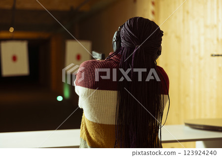 Woman in firing range doing recreational shooting activity with pistol, having fun hitting targets. Person in shooting gallery training with firearm, sharpening skills, developing muscle memory 123924240
