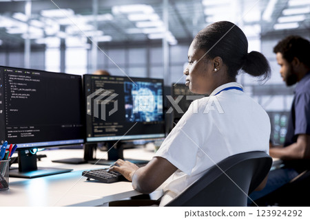 Server farm IT expert doing AI research, creating and implementing algorithms using neural networks. African american woman in data center using artificial intelligence computational models 123924292