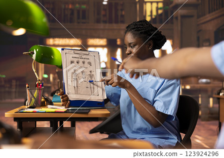 Future nurses studying anatomy class notes in a university library, reviewing courses and preparing for exams. Black med school students working together for their medical careers. 123924296