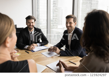 Businesspeople engaged in lively, positive discussion, gathered at conference table 123924297