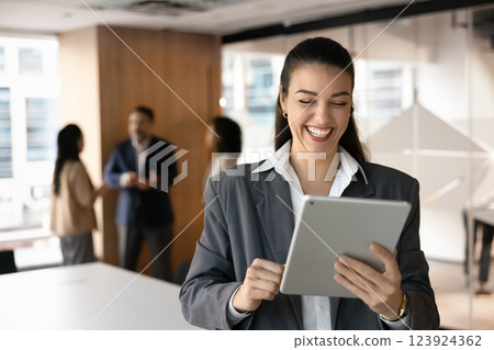 Excited cheerful young businessman using tablet in office meeting space Excited cheerful young businessman using tablet in office meeting space 123924362