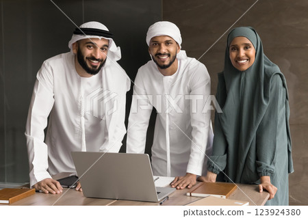 Three Arabian teammates dressed in traditional attire posing for camera 123924380
