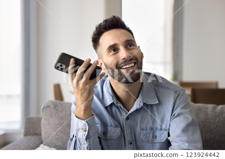 Smiling man holding smartphone listening received audio message 123924442