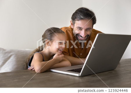 Joyful father and daughter watching comedy family movie on laptop 123924446