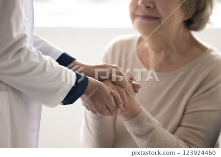 Caring doctor nurse caretaker hold sick elderly person hands closeup Caring doctor nurse caretaker hold sick elderly person hands closeup 123924460