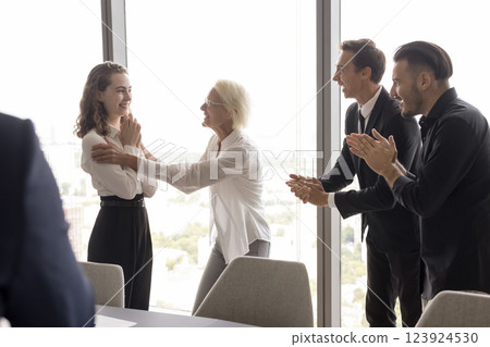 Mature female boss praise young girl employee before applauding teammates Mature female boss praise young girl employee before applauding teammates 123924530