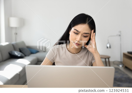 Woman sitting at her laptop, looking concerned or stressed Woman sitting at her laptop, looking concerned or stressed 123924531