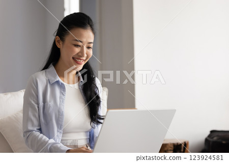 Positive online project manager working at laptop from home Positive online project manager working at laptop from home 123924581