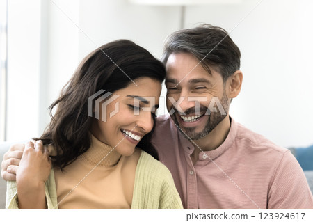 Beautiful multiethnic couple in love sit close together on sofa 123924617