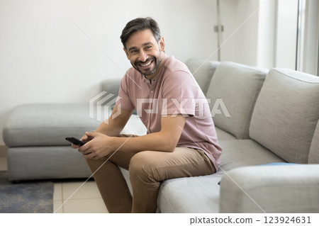 Middle-aged man sitting on couch with mobile phone Middle-aged man sitting on couch with mobile phone 123924631