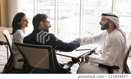 Two multicultural European and Arabian men engaged in firm handshake Two multicultural European and Arabian men engaged in firm handshake 123924647
