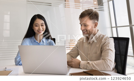 Two smiling young multiethnic colleagues work on project using notebook Two smiling young multiethnic colleagues work on project using notebook 123924650