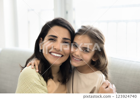 Closeup portrait beautiful mother and daughter cuddling seated on couch 123924740