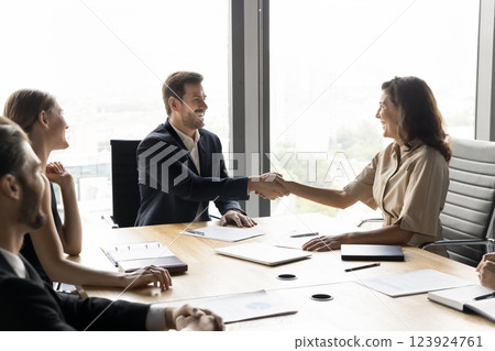 Group of businesspeople shaking hands seated at conference table 123924761