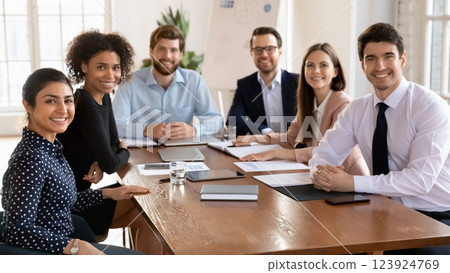 Businesspeople posing for camera gathered together at conference table Businesspeople posing for camera gathered together at conference table 123924769