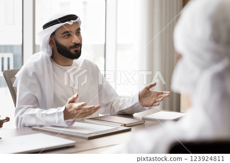 Young Arabic businessman in traditional kandora engaged in conversation Young Arabic businessman in traditional kandora engaged in conversation 123924811