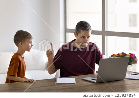 Father working on laptop while his little son asking attention Father working on laptop while his little son asking attention 123924854