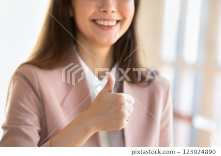 Closeup smiling businesswoman dressed in formal attire showing thumbs up Closeup smiling businesswoman dressed in formal attire showing thumbs up 123924890