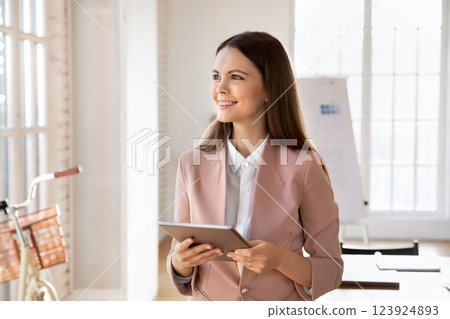 Creative businessperson standing in modern office with digital tablet Creative businessperson standing in modern office with digital tablet 123924893