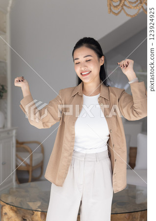 Happy Asian woman dancing at home with closed eyes Happy Asian woman dancing at home with closed eyes 123924925