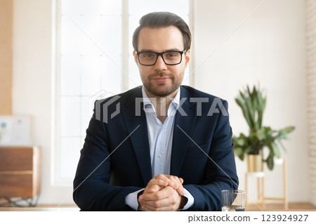 Businessman looking at camera, engaged in telemeeting event by business Businessman looking at camera, engaged in telemeeting event by business 123924927