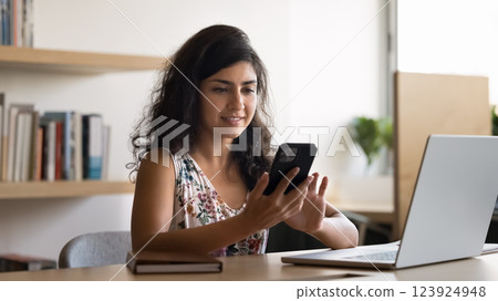 Smiling female student text message on smartphone screen before notebook 123924948