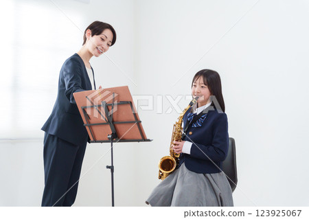 一位吹奏薩克斯風的銅管樂隊成員和一位女老師 一位吹奏薩克斯風的銅管樂隊成員和一位女老師 123925067