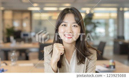 一位年輕女子在辦公室擺姿勢，笑容燦爛 123925088