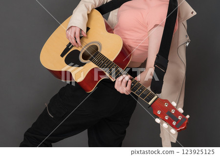 Unrecognizable woman guitarist playing her Spanish six string acoustic guitar and enjoying strumming string instrument during her performance on stage. Stylish and creativity female guitar player 123925125