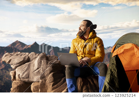 Tech savvy hiker having a technology obsession and working on a mountain peak, always connected to the internet with strong signal. Workaholic traveler does remote work on a hill. 123925214