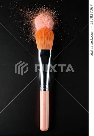 Make-up brush with Peach Fuzz powder explosion isolated in a black background with Generative AI. 123927367