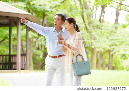 Senior couple traveling and looking at smartphone Senior couple traveling and looking at smartphone 123927675