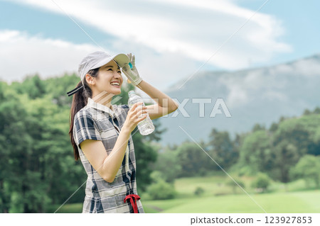 Golfer woman drinking water on golf course Golfer woman drinking water on golf course 123927853
