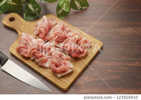 將豬肩肉切成薄片，放在砧板上 123928410
