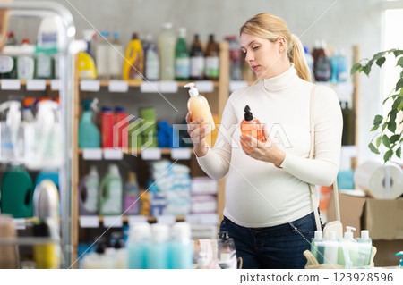 Interested pregnant woman choosing liquid soap in supermarket 123928596