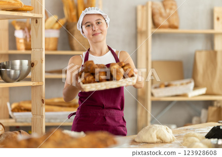 Teen girl holding croissants in square wicker basket 123928608