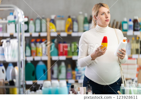 Thoughtful pregnant woman choosing sunscreen in personal care store 123928611
