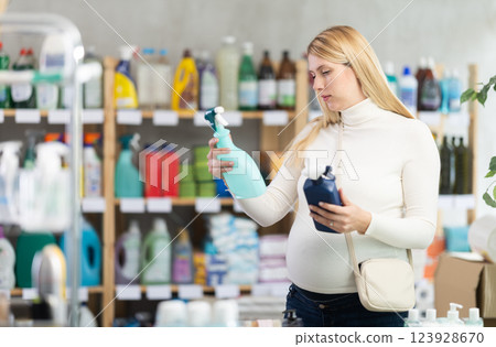 Pregnant woman choosing safe glass cleaner spray in supermarket 123928670