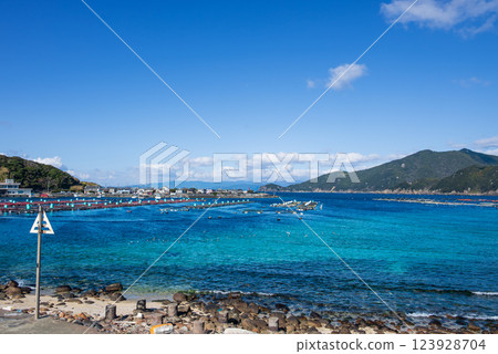 A coastline with floating fish ponds in the beautiful emerald green sea with a view of the cape A coastline with floating fish ponds in the beautiful emerald green sea with a view of the cape 123928704