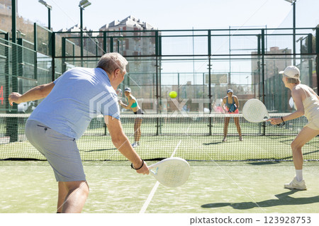 Motivated senior man playing padel with his teammate in court 123928753