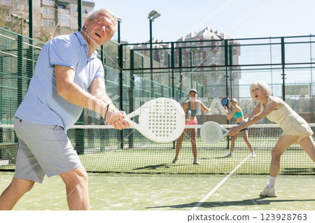 Motivated senior man playing padel with his teammate in court 123928763