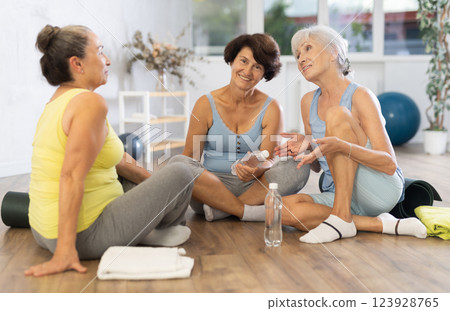 Group of elderly women in gym communicate after training and discuss plans for evening Group of elderly women in gym communicate after training and discuss plans for evening 123928765
