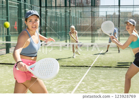 Two young motivated female padel players playing together in court 123928769