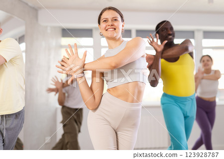 Active multinational men and women of different ages practicing Hip-hop dance in training hall during dancing classes 123928787