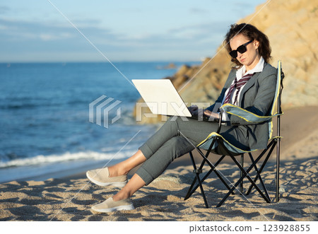 Professional woman in a suit working remotely on a laptop by the seaside 123928855